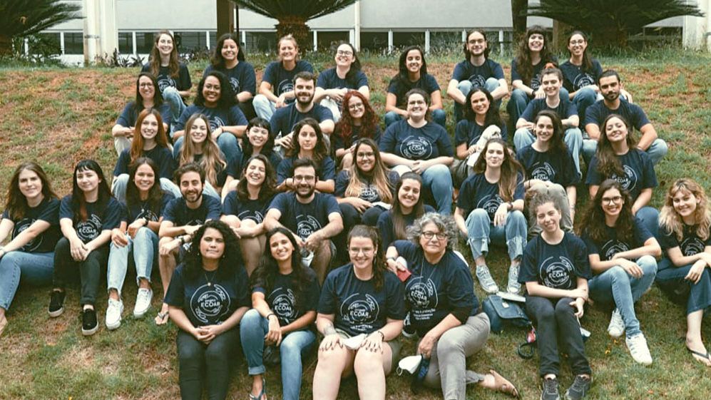 ecoar-amplia-insercao-escolas Dezenas de profissionais do Projeto Ecoar sentados em um gramado