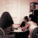 Três profissionais de pesquisa do GEP-inPsi sentadas a uma mesa